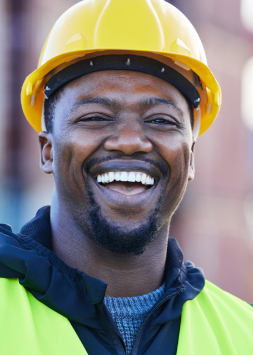 An image of a happy utility worker wearing a construction hat and a high vis jacket